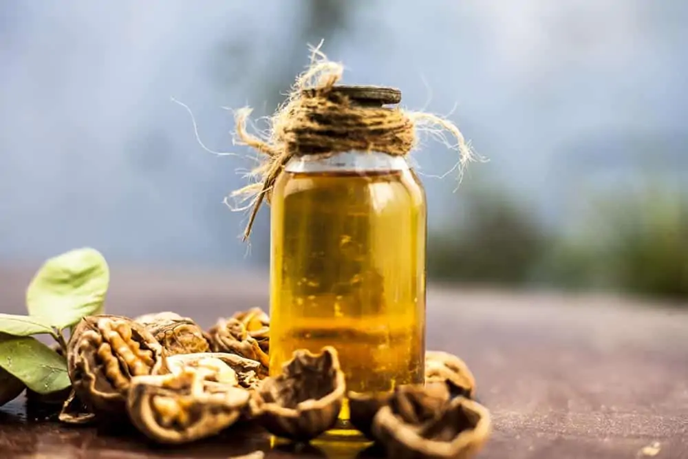 Flacon d'huile de noix avec des noix déposés sur un table en bois